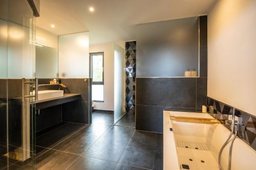 uma casa de banho com um lavatório, uma banheira e um espelho. em Boutiquehotel Genusswerk Eifel em Körperich