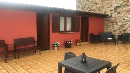 eine Terrasse mit einem Tisch, Stühlen und roten Wänden in der Unterkunft Posada El Nozal in Seña
