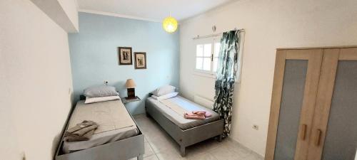 Cette chambre comprend 2 lits et une fenêtre. dans l'établissement The Athenian Riviera Summer Nest, à Anavyssos