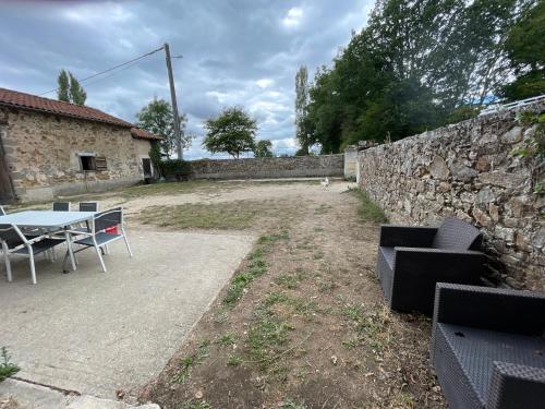 a patio with a table and a stone wall at Ferme Gite Equestre En Charente in Confolens