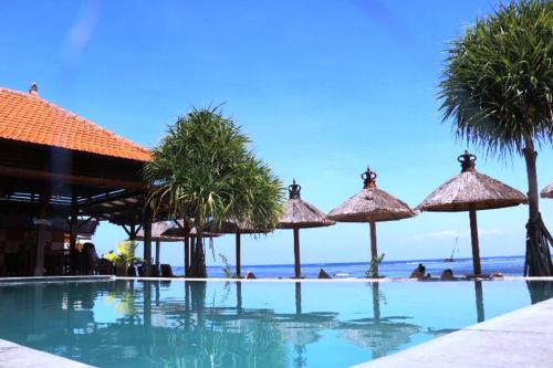 レンボンガン島にあるPemedal Beach Resortのパラソルと海を備えたスイミングプール