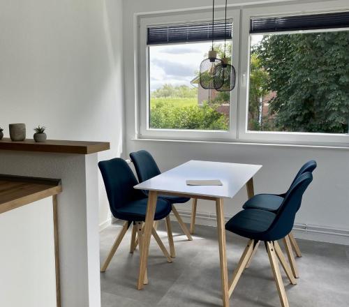 une salle à manger avec une table blanche et des chaises bleues dans l'établissement Ferienwohnung Brandung - Haus Seeschwalbe, à Schillig