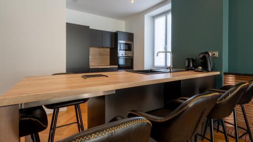 a kitchen with a wooden counter with chairs around it at L'art déco, T3 Terrasse, classé meublé de tourisme in Rodez