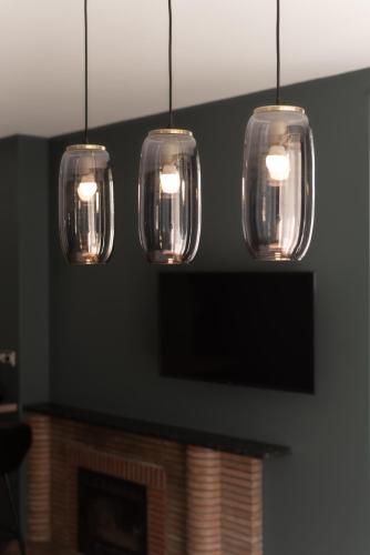 a group of five lights hanging over a fireplace at L'art déco, T3 Terrasse, classé meublé de tourisme in Rodez