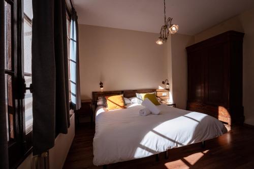 a bedroom with a bed with white sheets and yellow pillows at Hotel Mas de Xaxas in Camprodon