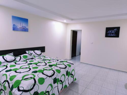 a bedroom with a bed with a green and white comforter at Abuja Modern Apartments in Abuja