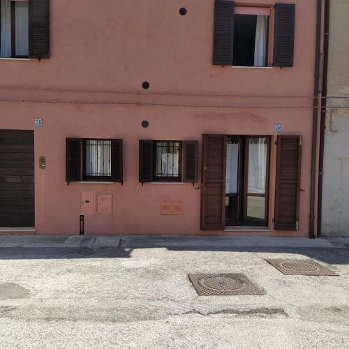 a pink building with doors and windows on it at Casa Lambertina in Senigallia
