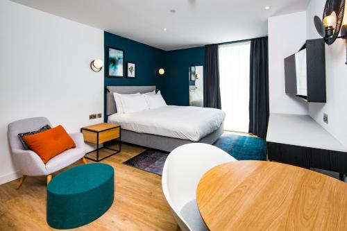 Staybridge Suites - Cardiff, an IHG Hotel في كارديف: غرفة نوم بسرير وطاولة وكرسي