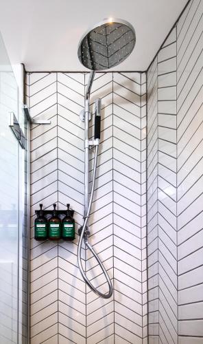 a bathroom with a shower with green bottles on a wall at Staybridge Suites - Cardiff by IHG in Cardiff