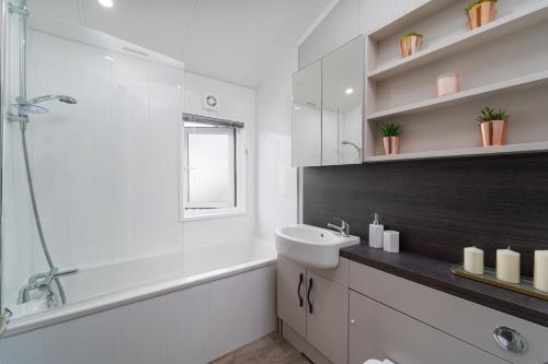 een witte badkamer met een wastafel, een bad en een douche bij Number Four - Piran View in Padstow