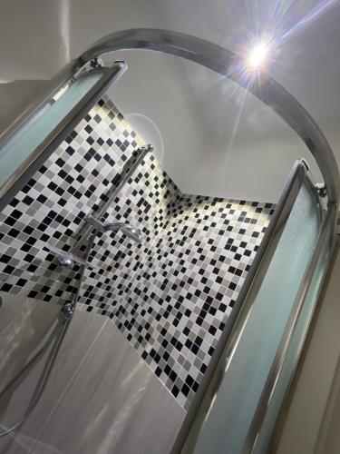 a glass shower with a black and white checkered floor at Casetta rosa Taormina in Taormina