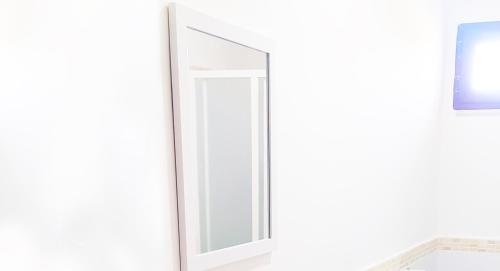 a mirror on a white wall in a bathroom at Casa Giada sul mare in Torrenova