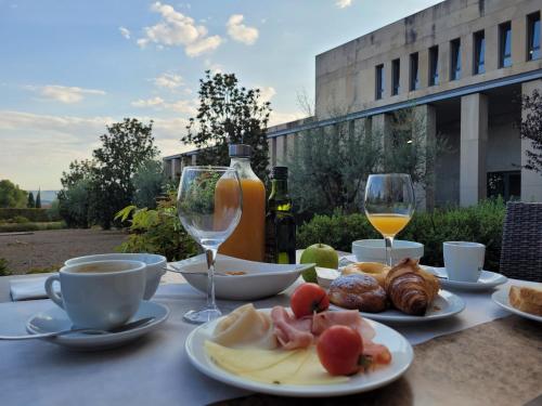 una mesa con platos de comida y dos copas de vino en Hostatgeria de Poblet en Poblet