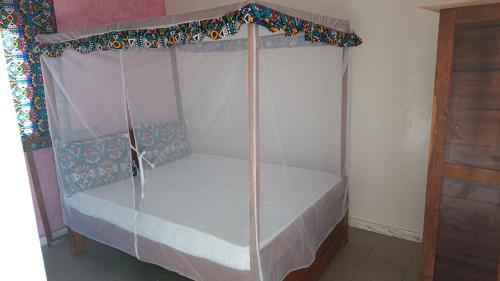 a bed with a canopy in a room at La Case a Mamy in Nianing
