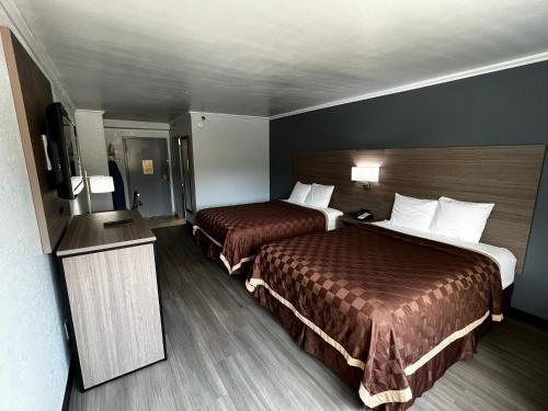 a hotel room with two beds and a flat screen tv at Super 8 by Wyndham Fort Worth Entertainment District in Fort Worth