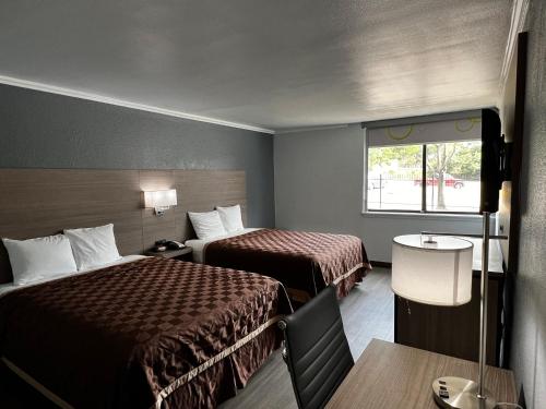 a hotel room with two beds and a table at Super 8 by Wyndham Fort Worth Entertainment District in Fort Worth