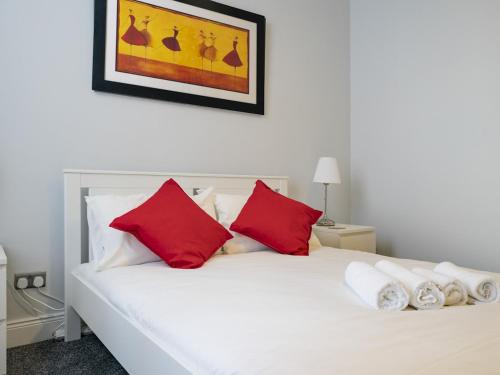 a white bed with red pillows in a bedroom at Pass the Keys Pristine 1BR Apt Queens Uni Walk Everywhere in Belfast