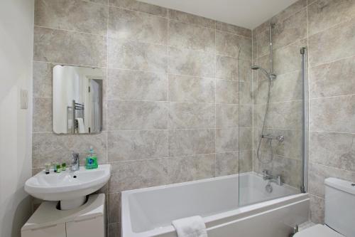 a bathroom with a tub and a sink and a toilet at Theodora Suites 2 by Kasar Stays in Kent