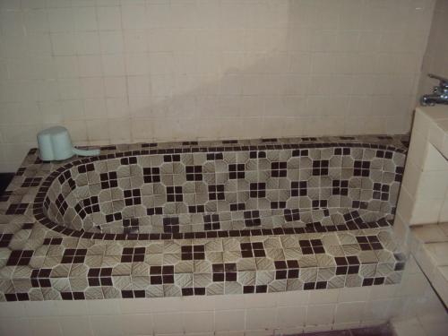 a bathroom with a tiled bath tub with a trash can at Puri Agung Inn in Sidemen