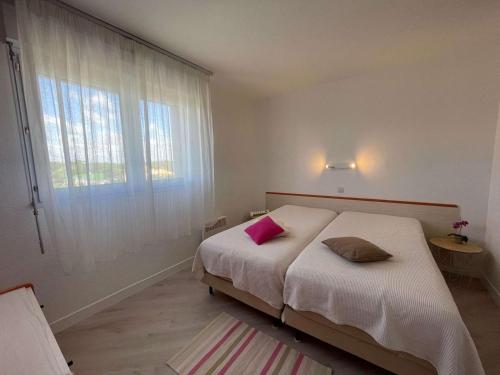 une chambre avec un lit avec deux oreillers dessus dans l'établissement Appartement lumineux, piscine chauffée, parking privatif - FR-1-224C-305, à Saint-Jean-de-Monts