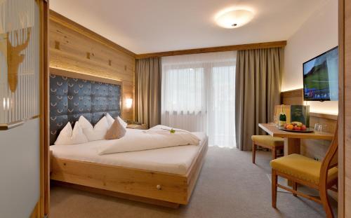 a hotel room with a bed and a desk at Hotel Gasthof Jäger Zillertal in Schlitters