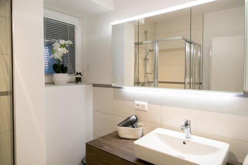 La salle de bains blanche est pourvue d'un lavabo et d'un miroir. dans l'établissement Ferienwohnungen Kircher Villa Baudisch, à Sattendorf