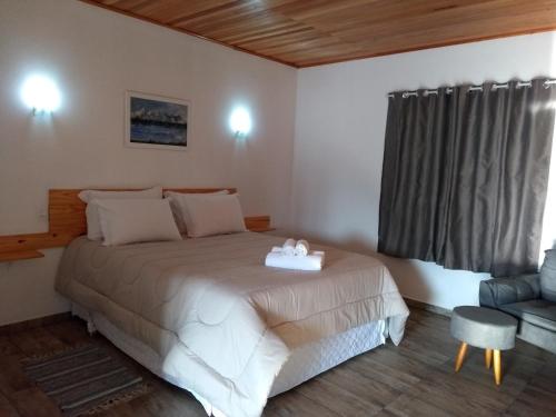 a bedroom with a bed and a chair and a window at POUSADA AURORA in Mundo Novo