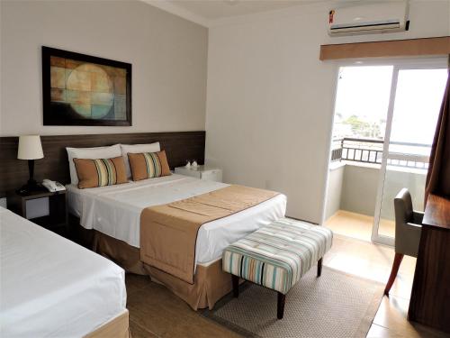 a hotel room with two beds and a window at Hotel Água Viva - By UP Hotel in Cachoeira Paulista