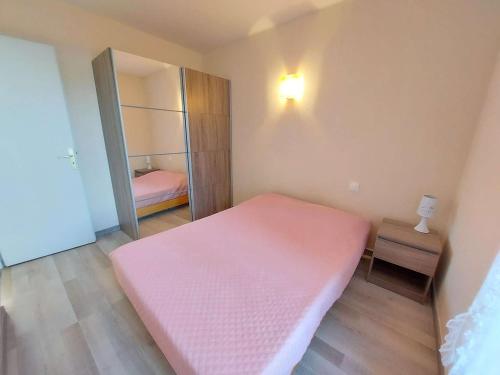 - une petite chambre avec un lit rose et un miroir dans l'établissement Appartement lumineux 4-6 pers avec terrasse, parking et cuisine équipée à Marseillan - FR-1-326-502, à Marseillan