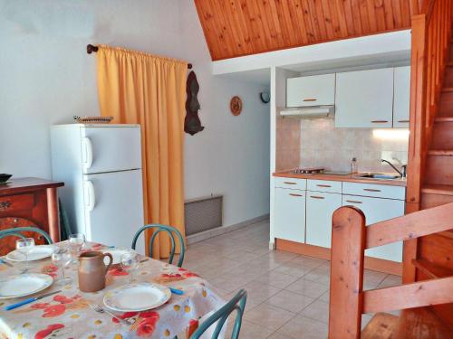une cuisine avec une table et un réfrigérateur blanc dans l'établissement Maison de vacances au canal, 2 chambres, animaux admis, parking privé - FR-1-387-86, à Marseillan