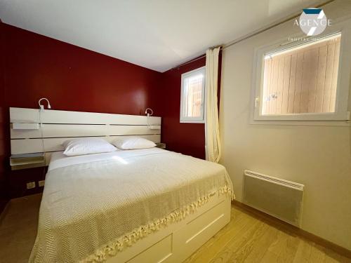 - une chambre avec un lit blanc aux murs rouges et une fenêtre dans l'établissement THE BLUE GOLF, à Sainte-Maxime