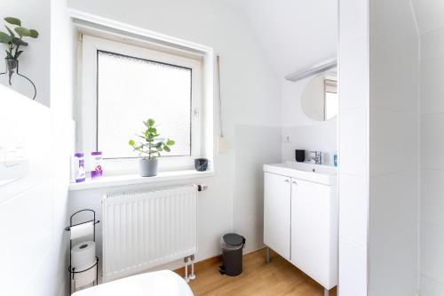uma casa de banho branca com um lavatório e uma janela em Stay Awesome - Modernes Apartment am Botanischen Garten em Kassel