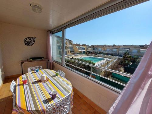 d'un balcon avec une table et une vue sur la piscine. dans l'établissement Appartement 2 pièces avec piscine et parking à Marseillan-Plage - FR-1-326-574, à Marseillan