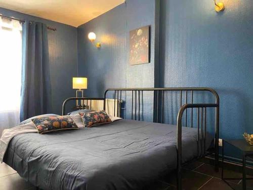 een slaapkamer met een bed met blauwe muren bij Le Duplex du Beffroi in Douai