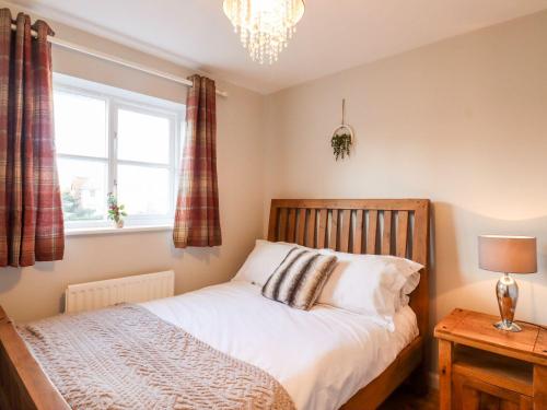 a bedroom with a bed and a window and a chandelier at Cherry Blossom Place in Tiptree