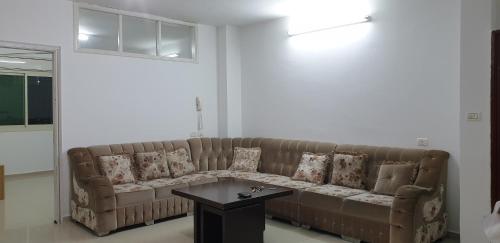 a living room with a brown couch and a table at Nice Apartment in Hebron Palestine in Khirbat an Naşārá