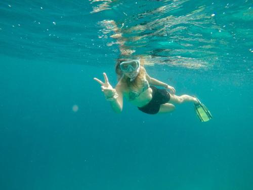 a woman swimming in the water with a bottle at Konut by Thakuru in Guraidhoo