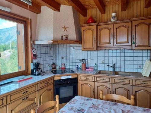 une cuisine avec des armoires en bois, une table et une fenêtre dans l'établissement Chalet familial 2*, proche pistes et centre, terrasse sud, vue montagnes - FR-1-618-10, à Albiez-Montrond
