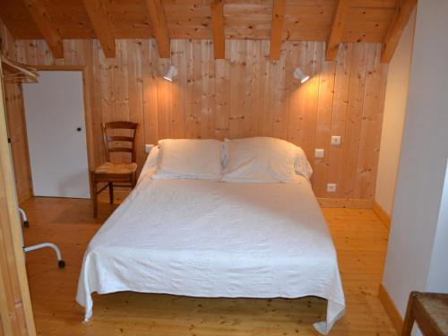 une chambre avec un lit dans une pièce aux murs en bois dans l'établissement Chalet confortable 2* avec poêle à granulés et jardin, accepte animaux - FR-1-618-16, à Albiez-Montrond