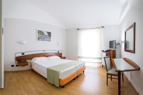 a bedroom with a bed and a desk and a window at Sardegna Termale Hotel&SPA in Sardara