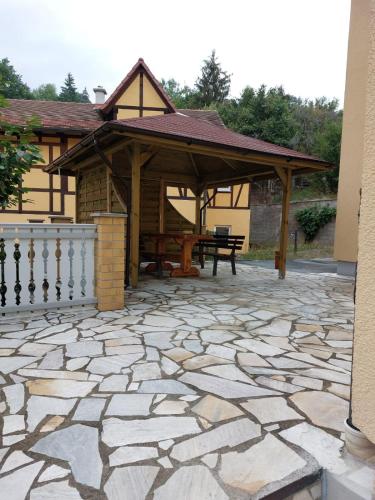 a pavilion with a table and a bench on a stone patio at FewoQuido 2 in Königsee