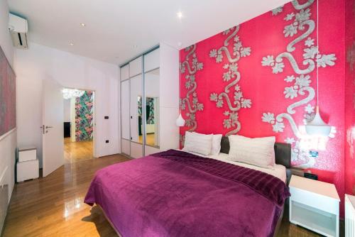 a bedroom with a purple bed and a pink wall at Agape Apartments in Zagreb