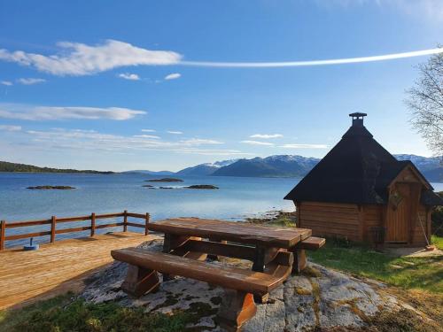 a wooden picnic table sitting next to a lake at Off-the-grid cabin on the island of Senja in northern Norway in Vangsvik