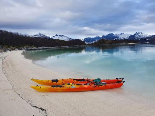 two kayaks on a beach next to the water at Off-the-grid cabin on the island of Senja in northern Norway in Vangsvik