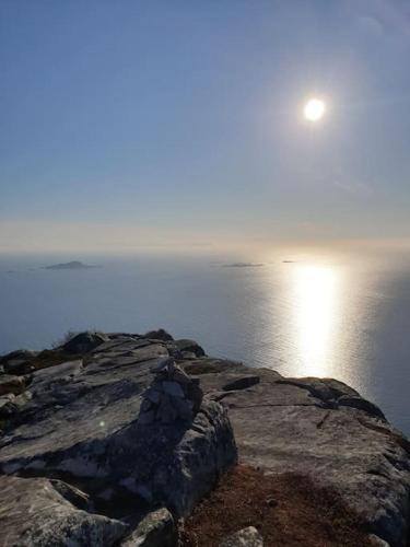 a moon sitting on top of a rock near the water at Off-the-grid cabin on the island of Senja in northern Norway in Vangsvik