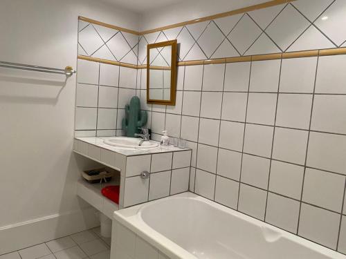 a white tiled bathroom with a tub and a sink at Le pigeonnier de Saint-Loup Bed and Breakfast in Saint-Loup-de-Varenne