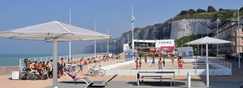 Grupa ludzi na plaży w pobliżu oceanu w obiekcie L'appart'2 charme, bord de mer. w mieście Saint-Valéry-en-Caux