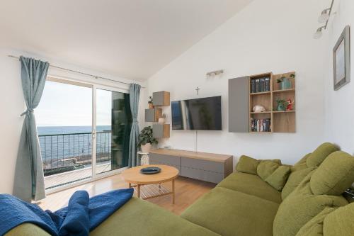 a living room with a green couch and a large window at Apartment by the sea in Podgora