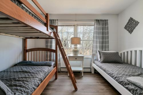 a bedroom with two bunk beds and a window at 3 BR Private Pondside View New Reno [Moose Lodge] in Bar Harbor