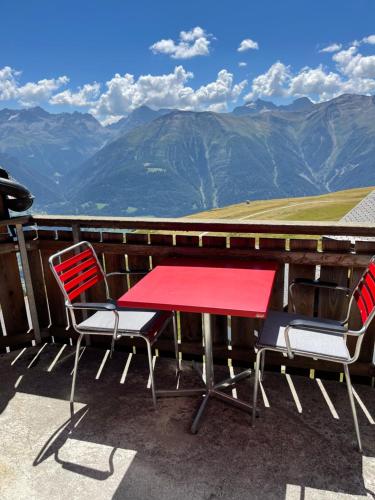 una mesa roja y sillas en un balcón con montañas en Mischabelblick en Fiesch